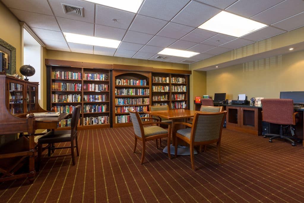 A cozy library with bookshelves, a table, and chairs for reading.