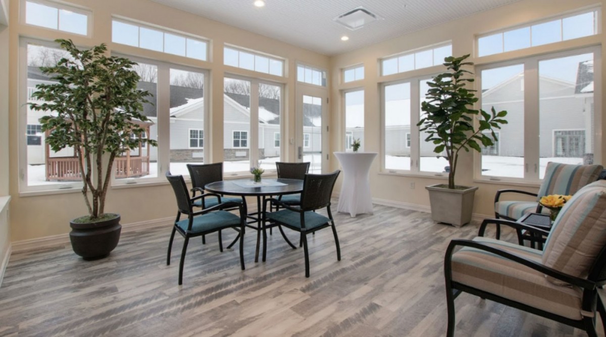 A bright and airy dining area with large windows and plants.