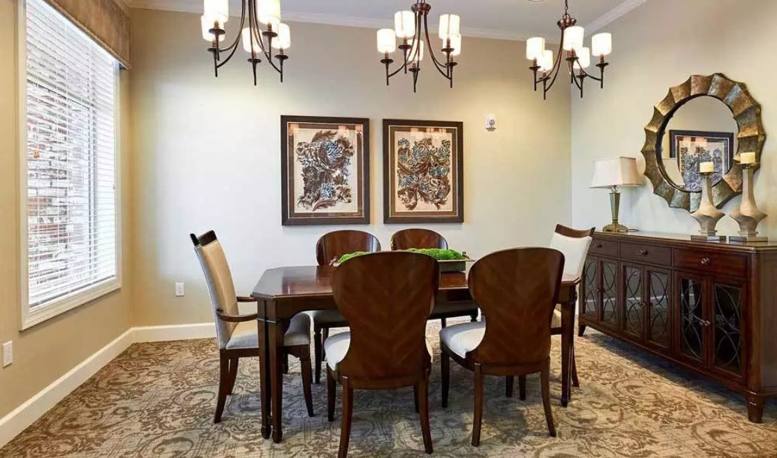 A cozy dining room featuring a wooden table and chairs, adorned with elegant chandeliers and decorative artwork on the walls.