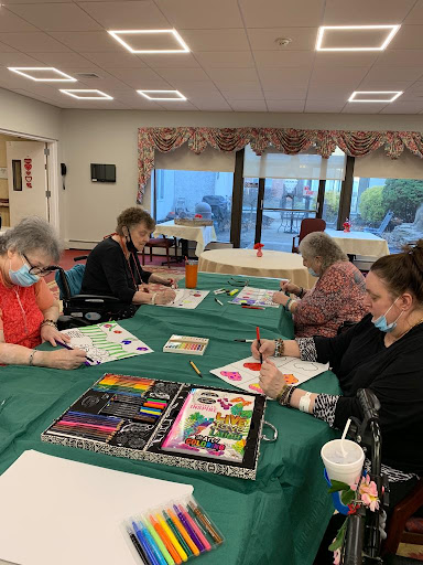 A group of older adults engaged in a painting session, showcasing their creativity and enjoying a social activity.