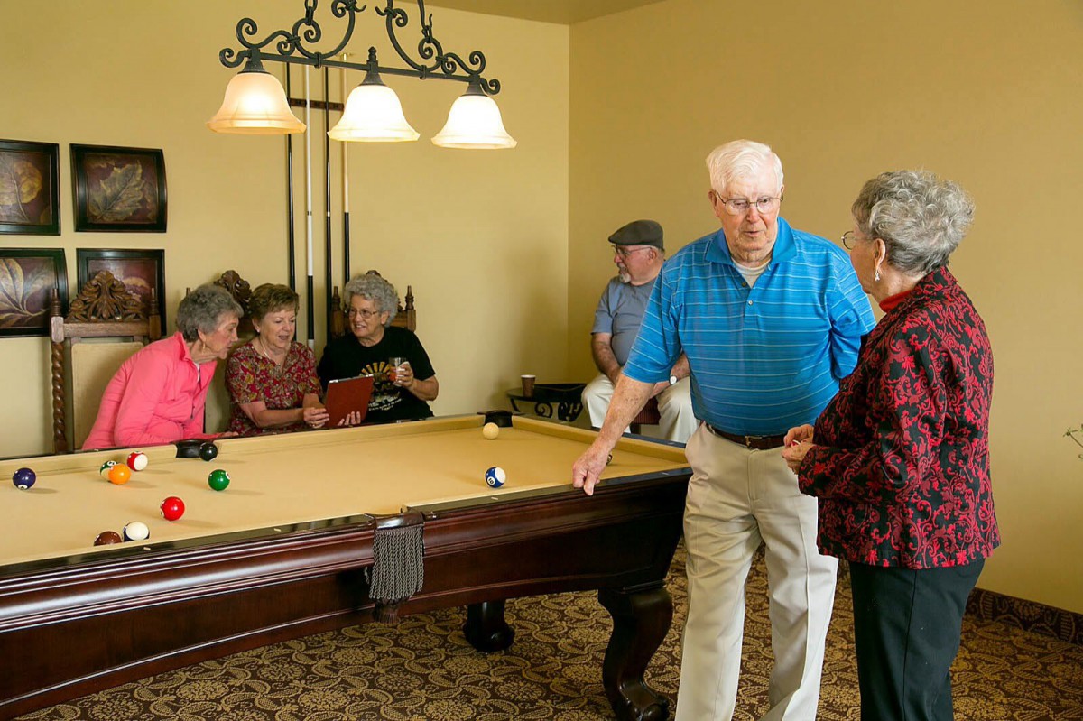 A group of seniors enjoying a game of billiards in a cozy indoor setting.