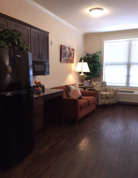 A cozy living room with dark wooden floors, featuring a sofa and armchair near a window.
