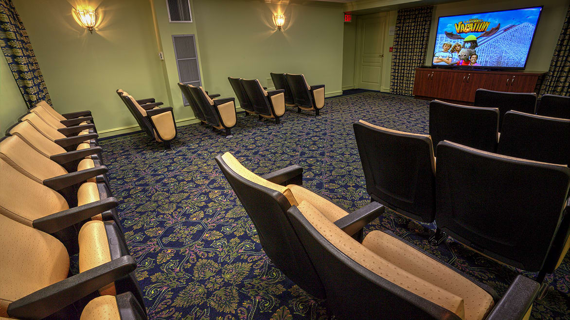 An empty movie theater with rows of comfortable chairs and a screen at the front.