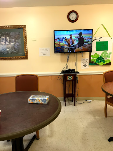 A view of a common area featuring a television, tables, and chairs.