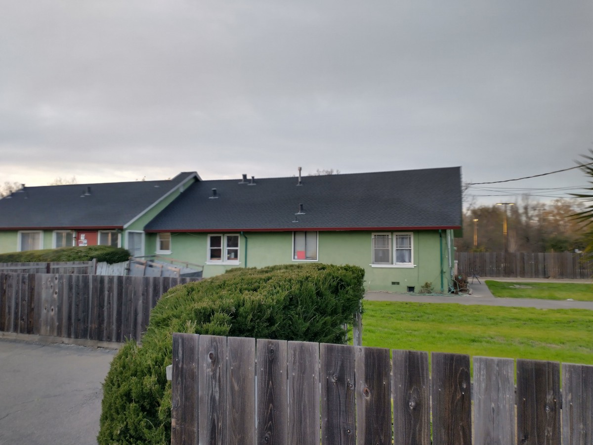 A residential house with a wooden fence and cloudy sky.