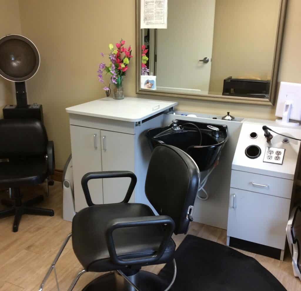 A cozy hair salon with a barber chair, sink, and mirror.