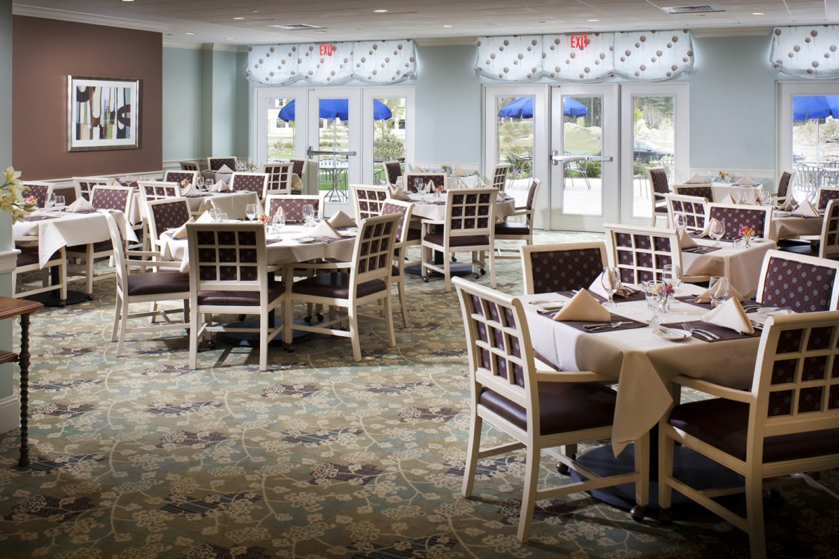 An empty restaurant dining room with neatly arranged tables and chairs.