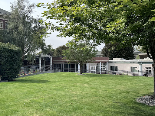 A serene outdoor space featuring a landscaped lawn, modern buildings, and lush greenery.