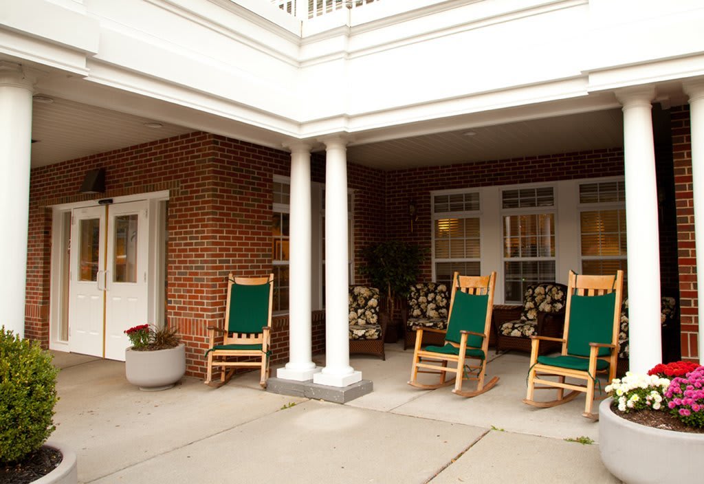 A cozy porch area with rocking chairs in front of a brick building.