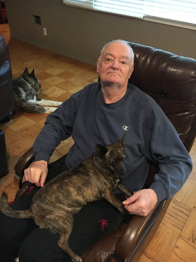 A man sitting comfortably in a chair with a dog resting on his lap, enjoying a relaxing moment indoors.