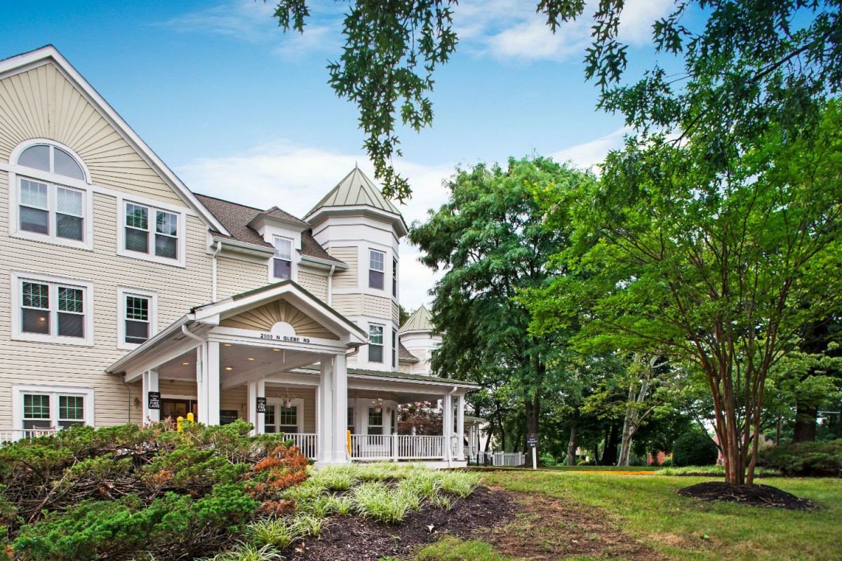 A charming residential house with a wraparound porch and lush greenery.
