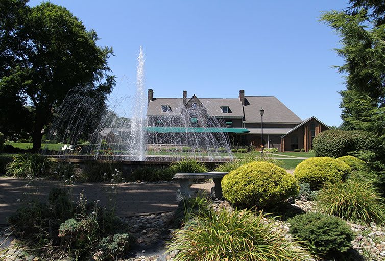 A beautiful garden with a large fountain in front of a rustic building.