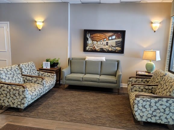 A cozy living room setup with a sofa, patterned chairs, and wall artwork.