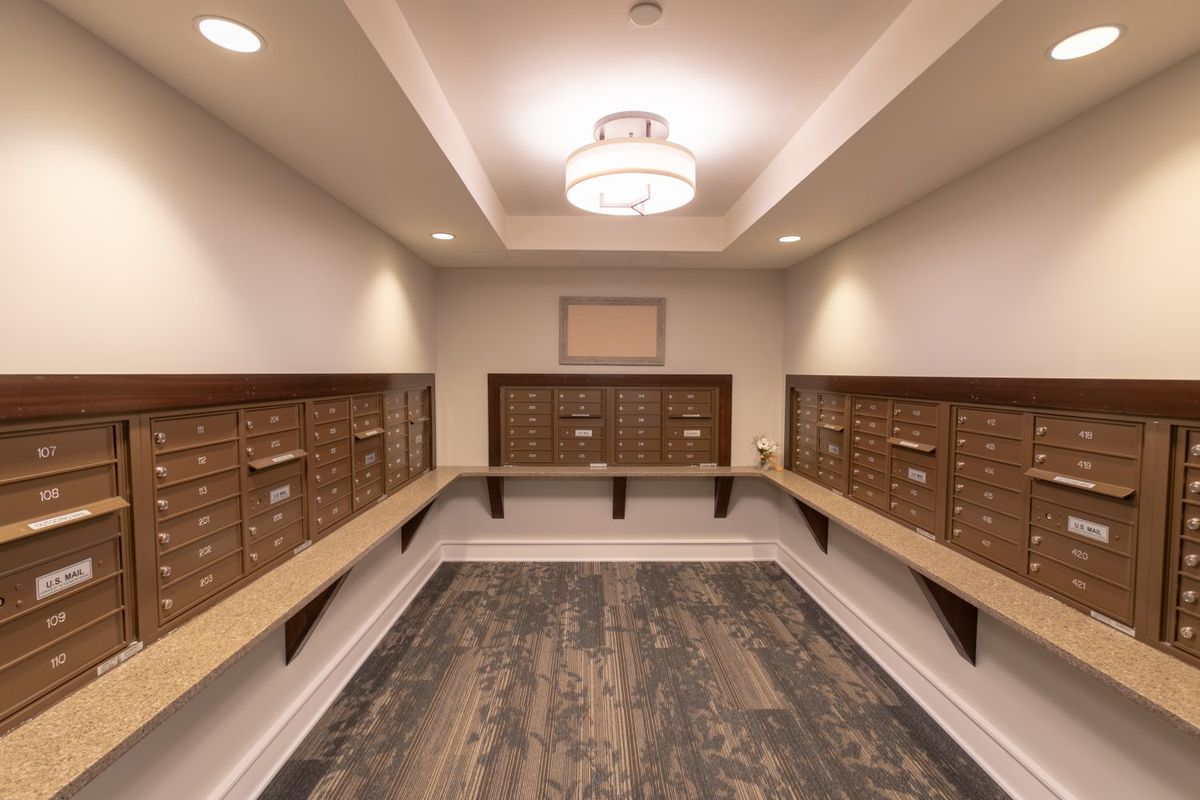 An organized mailroom with rows of mailboxes and warm lighting.