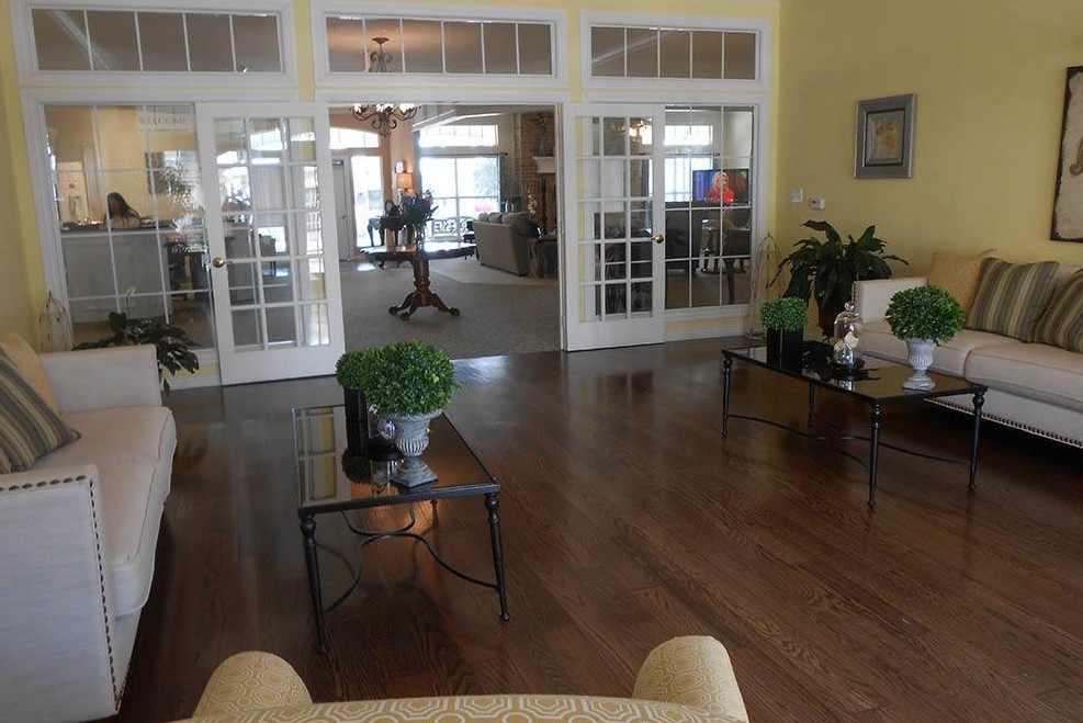 A spacious living room with wooden flooring and glass doors leading to another area of the house.