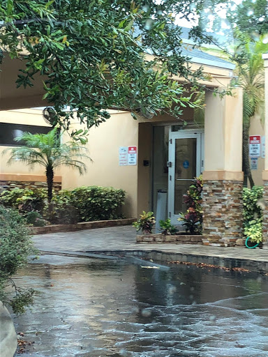 A welcoming entrance to a building surrounded by lush landscaping and palm trees.