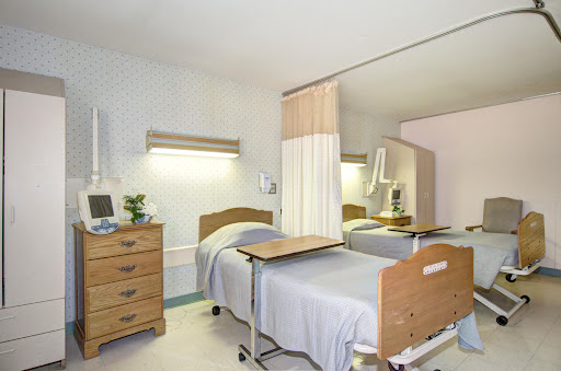 A well-lit and clean hospital patient room featuring two beds, modern medical furniture, and a soothing color palette.