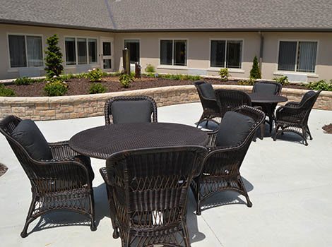 An outdoor patio area with wicker furniture and a building in the background.