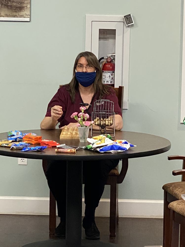 A person wearing a mask is seated at a table with snacks.