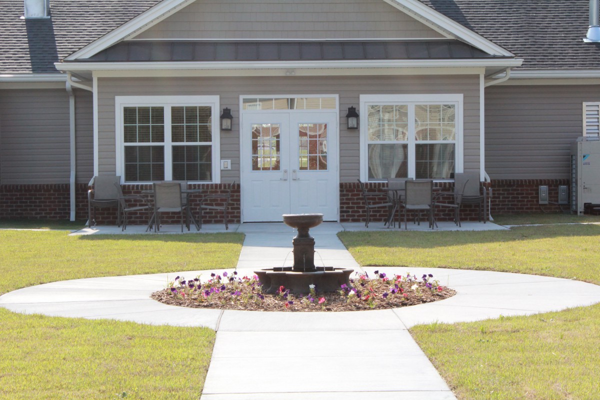 A charming house with a central fountain and well-maintained lawn.