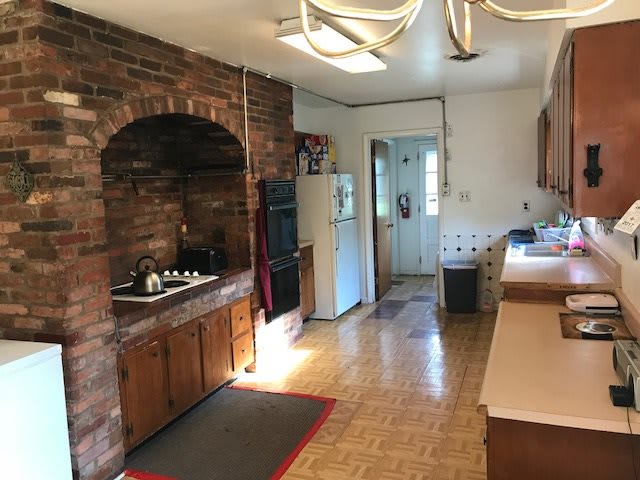 A cozy kitchen with a brick wall, featuring a stove and wooden cabinets.
