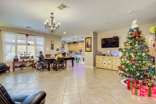 A cozy living room decorated for the holidays, featuring a Christmas tree and two individuals in wheelchairs enjoying their time.