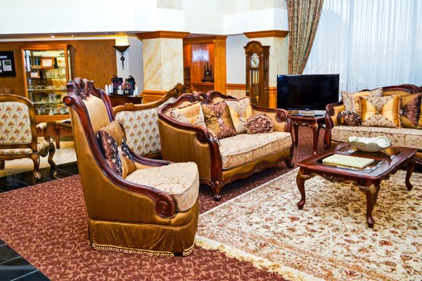 A traditionally decorated living room featuring elegant sofas, armchairs, and a grandfather clock.