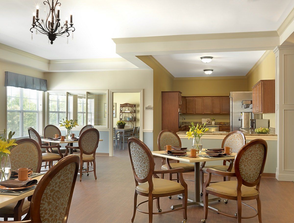 A bright and inviting dining room with elegant chairs and tables, adjacent to a kitchen area.