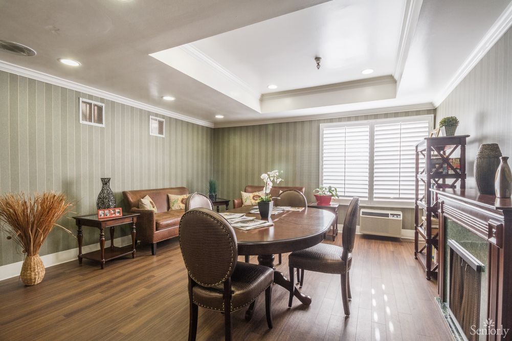 A cozy living room with a dining area, featuring a wooden table and chairs, comfortable sofa, and elegant decor.
