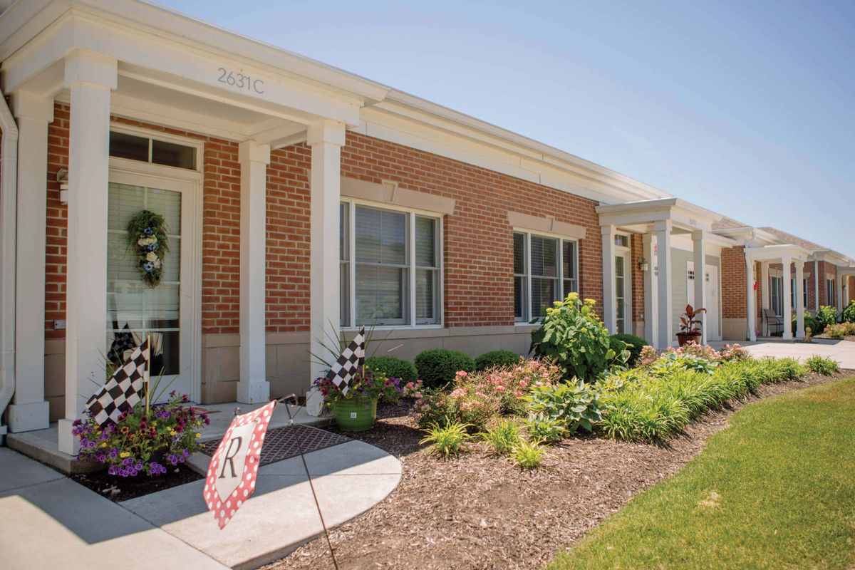 A charming brick residential house with well-maintained landscaping and a front pathway.