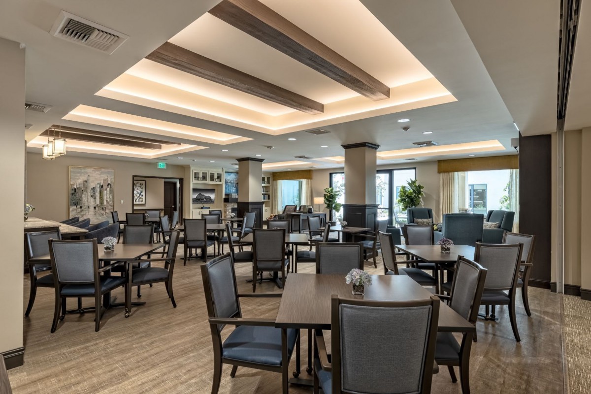 A modern and spacious dining room with neatly arranged tables and chairs, featuring warm lighting and a stylish interior design.