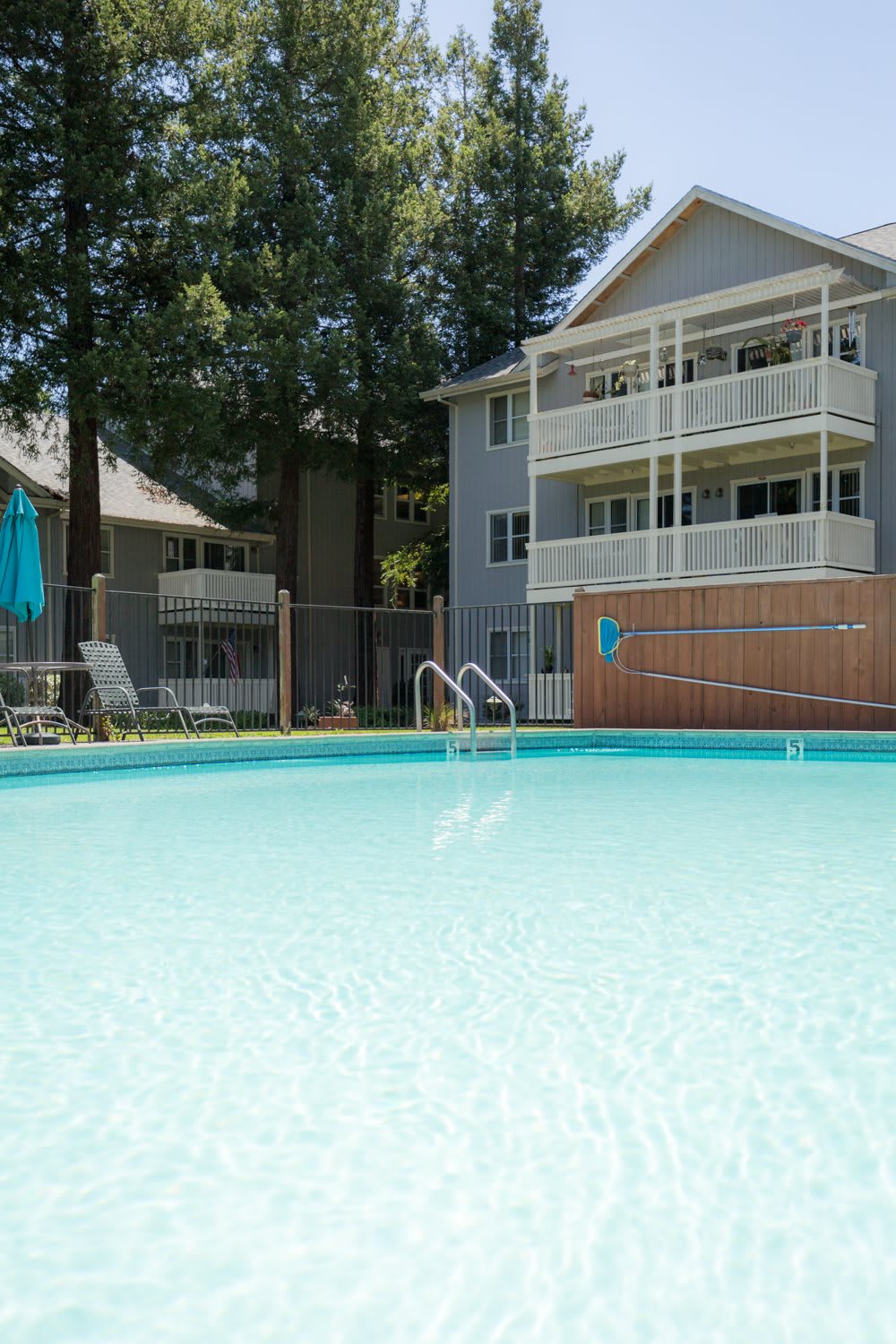 A refreshing swimming pool in front of an apartment complex on a sunny day.