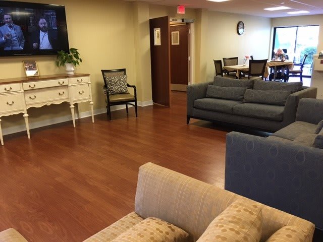A cozy living room area with sofas, chairs, a television, and hardwood flooring.
