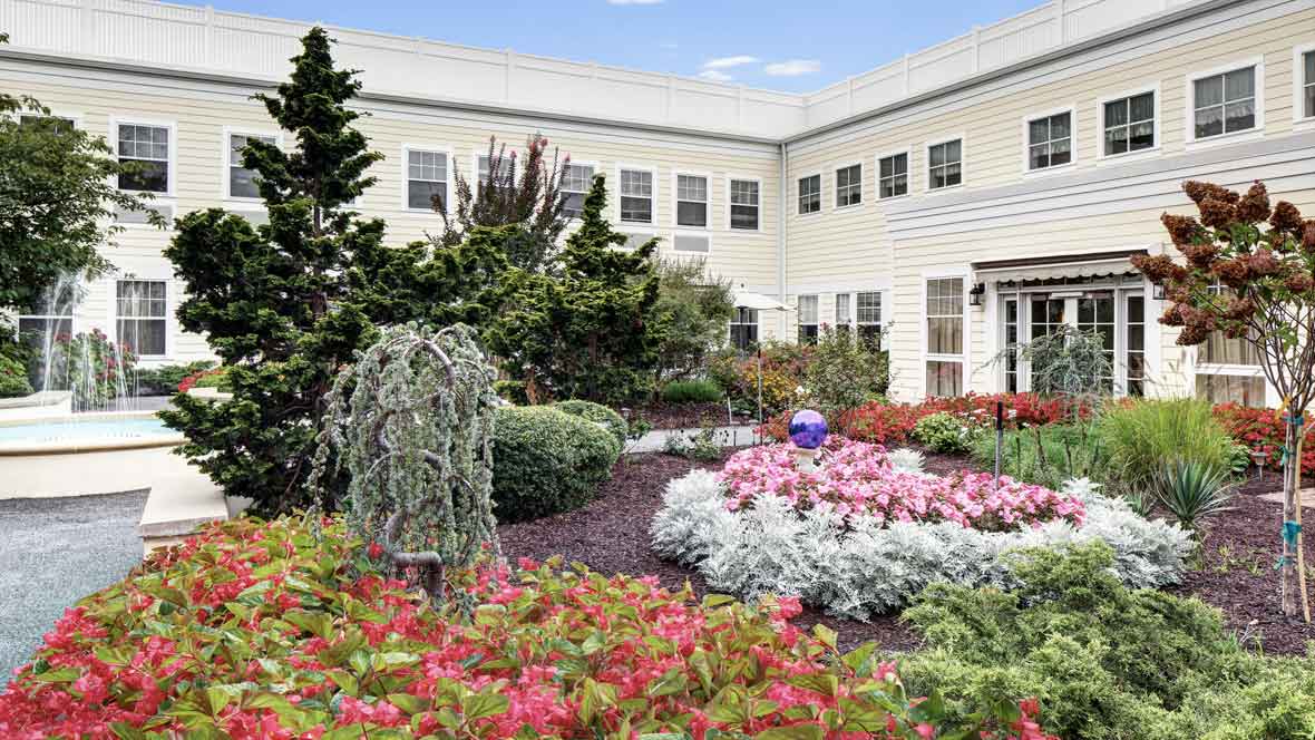 A beautifully landscaped garden with vibrant flowers in front of a white building.