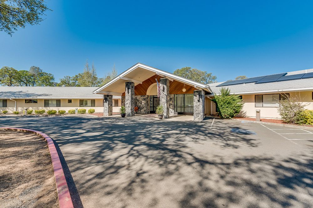 A sunny day view of a building entrance with a wide driveway.