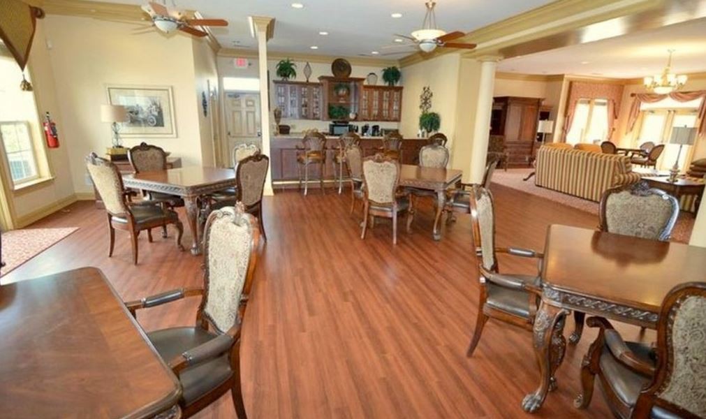 A well-lit dining room with wooden floors, tables, and chairs arranged in a cozy setting.