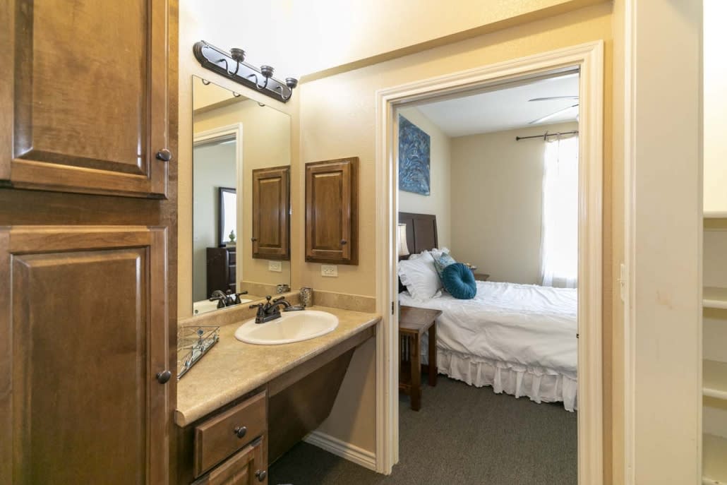 A cozy bedroom with an attached bathroom featuring a sink and mirror.