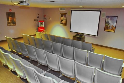 An empty small theater with a projection screen and rows of seats.