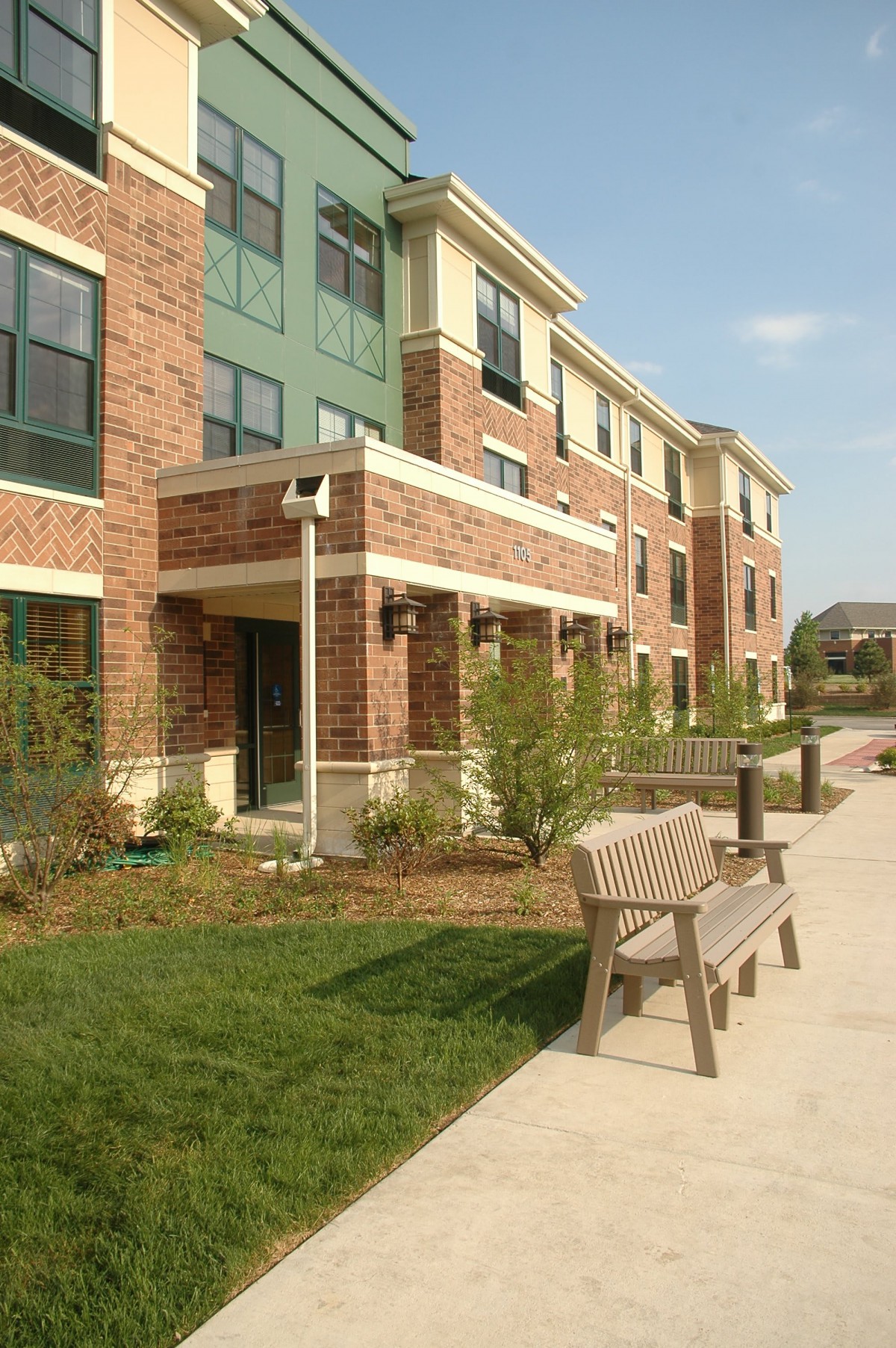 A residential apartment building with a bench and landscaped pathway.