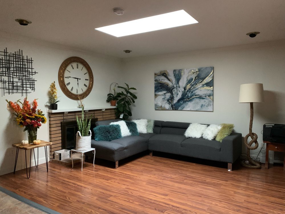 A cozy living room with a modern gray sectional sofa, wooden floors, and a bright skylight.