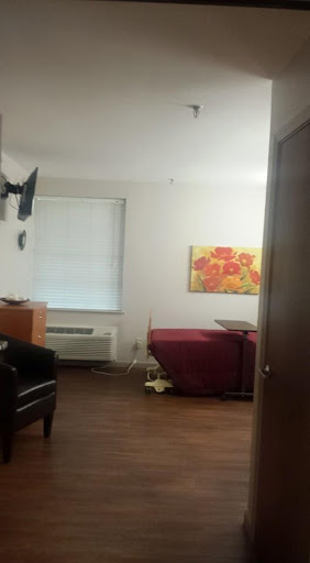 A cozy room featuring a bed, a chair, and artwork on the wall.