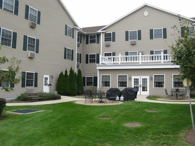 A multi-story residential building with a well-maintained lawn and patio area.