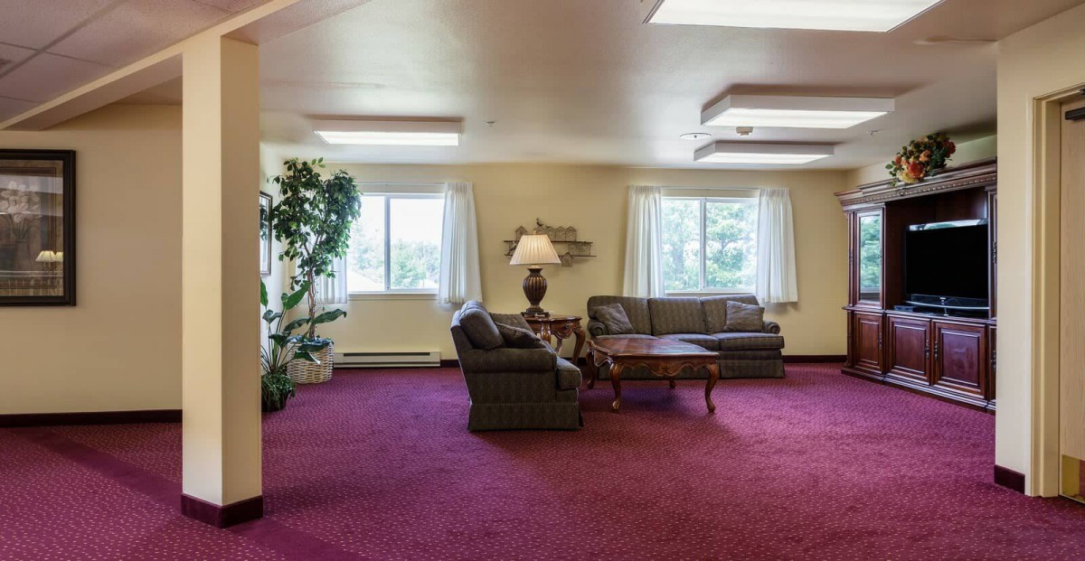 A cozy living room with sofas, a coffee table, and a lamp near large windows.