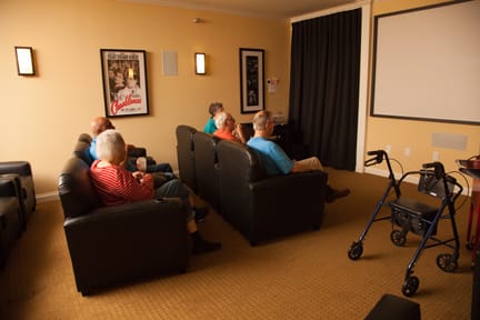 A group of seniors watching a movie in a cozy screening room.