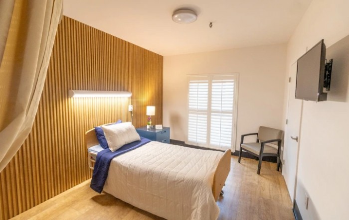 A minimalist bedroom with a single bed and wooden panel accents.