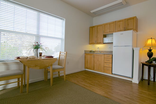 A cozy kitchen and dining area with wooden cabinets and a small dining table by the window.