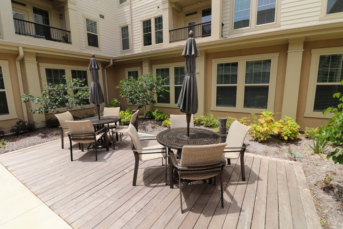 An inviting outdoor patio area featuring tables and chairs with umbrellas in an apartment courtyard.