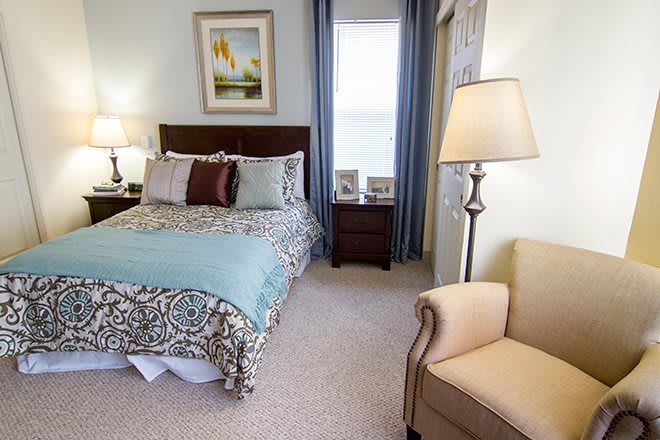 A cozy bedroom featuring a well-decorated bed, bedside tables, and a comfortable armchair.