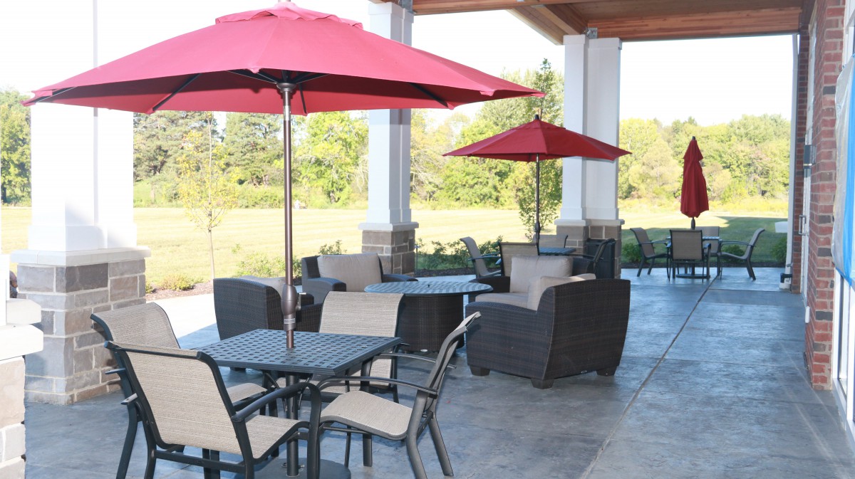 An inviting outdoor patio with red umbrellas and comfortable seating arrangements.