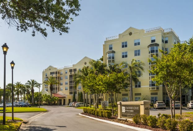 A sunny view of a residential condominium surrounded by palm trees and well-maintained landscaping.
